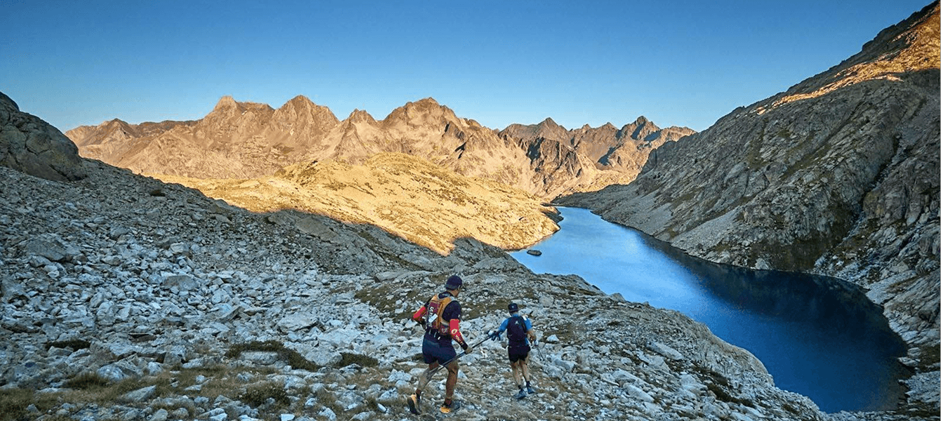Corredors corrent per un paisatge d'alta muntanya amb un llac als Pirineus